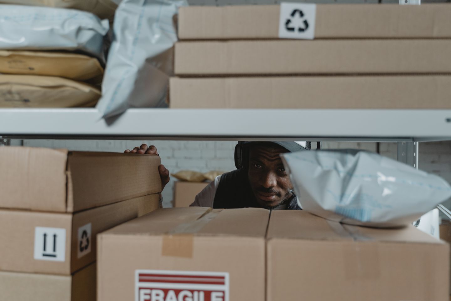 Warehouse worker inspecting packaged stock on shelving.