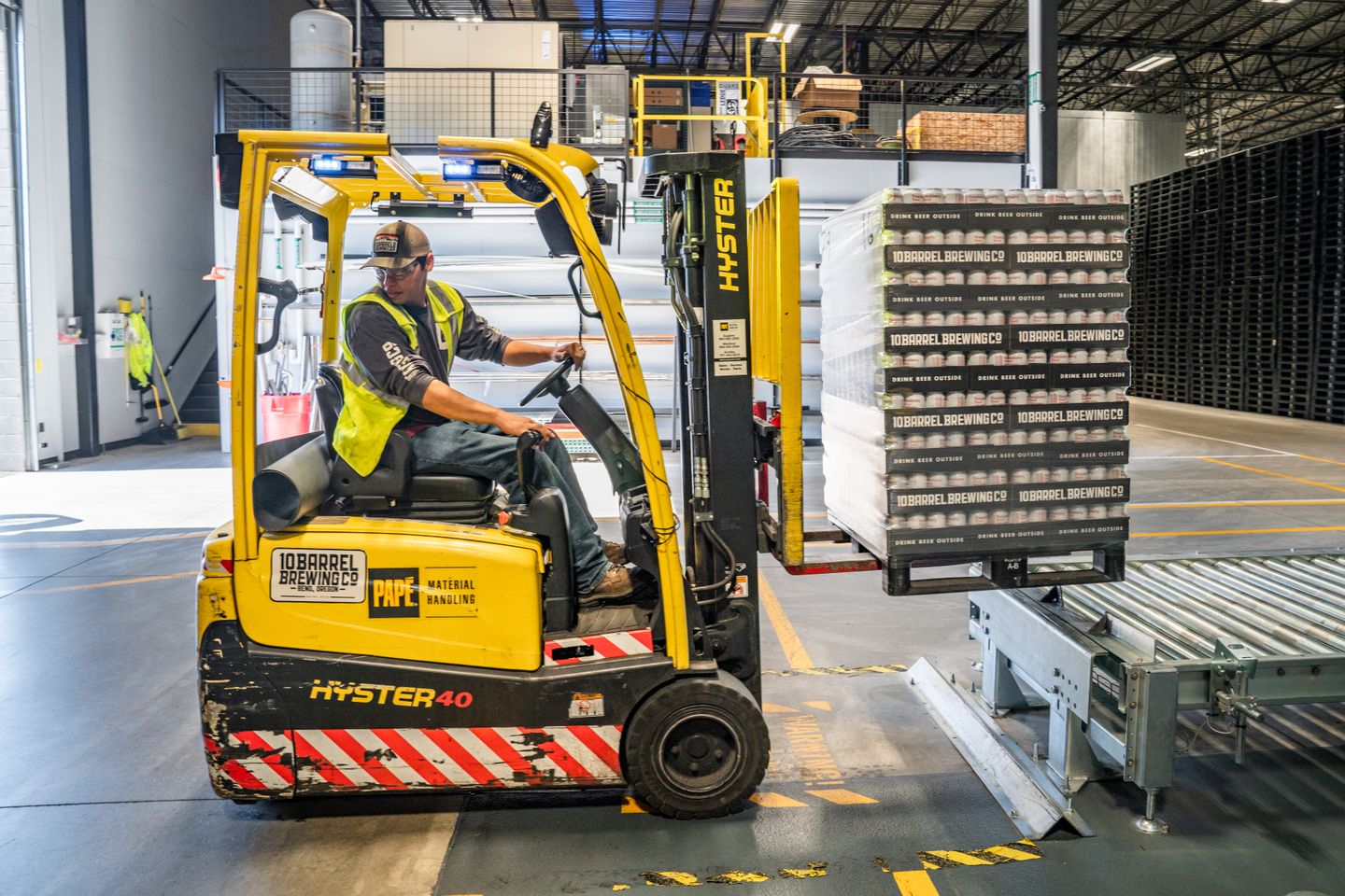 Forklift operator moving crates at a warehouse loading area.