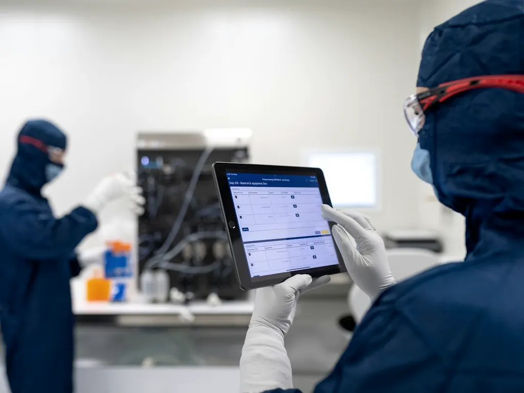 Technician reviewing live equipment status on a tablet beside connected production equipment